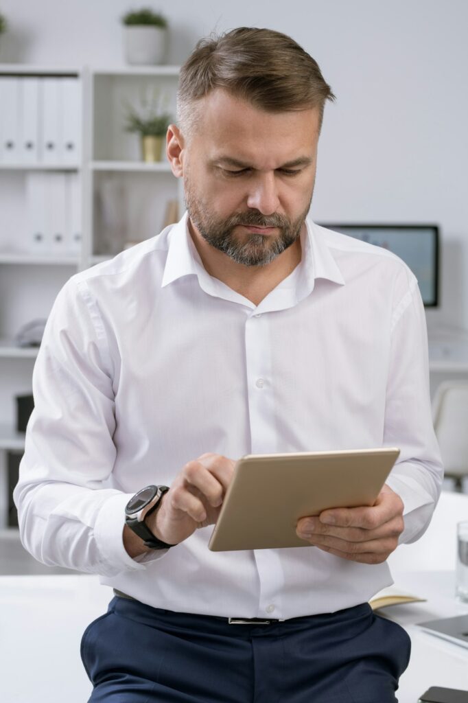 Elegant confident employer scrolling in touchpad while surfing for information